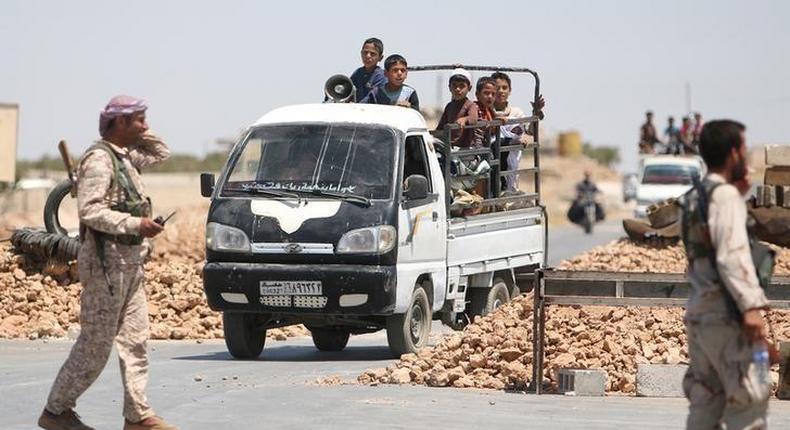 Syria Democratic Forces (SDF) fighters man a checkpoint as civilians on pick-up trucks evacuate from the southern districts of Manbij city after the SDF advanced into it in Aleppo Governorate, Syria, July 1, 2016. 