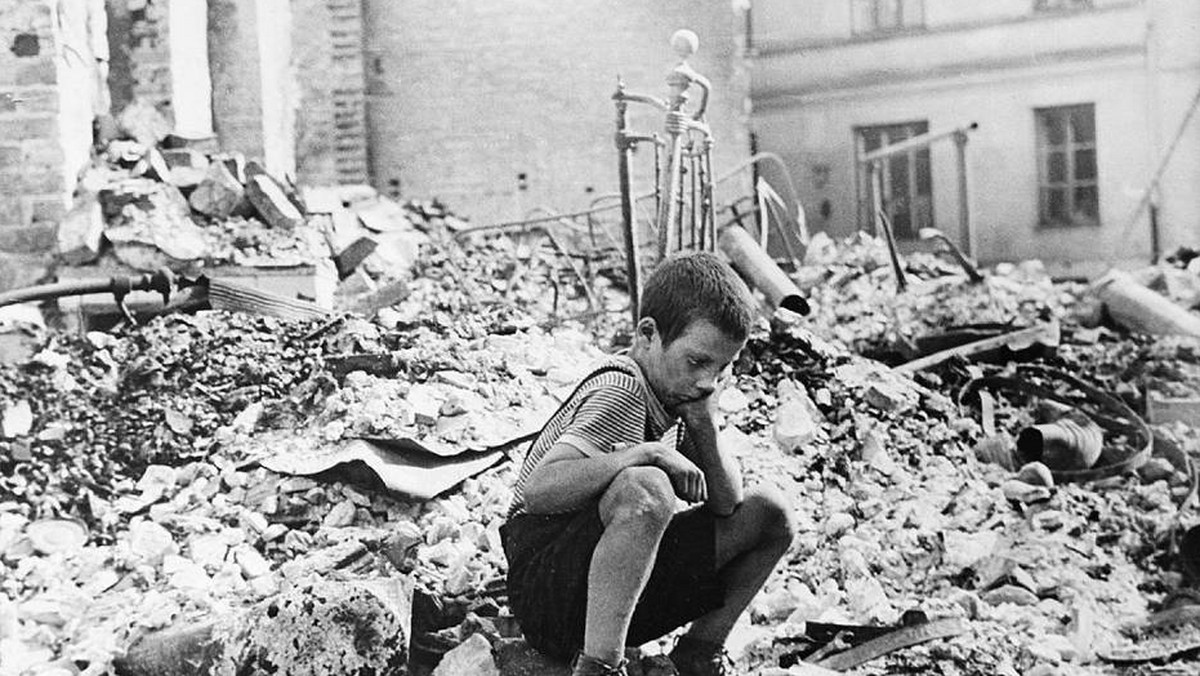 Chłopiec na gruzach zburzonego budynku w Warszawie