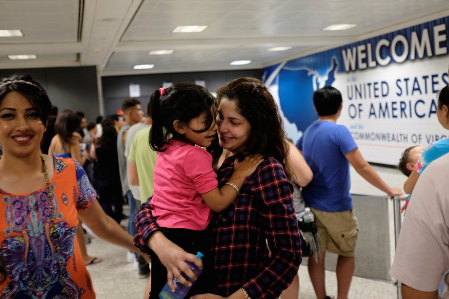 Zarfishan Zahid smiles as Sana Tahir holds Malaika Noman, 3, as the child arrives at Washington Dulles International Airport after a federal judge blocked the second ban on July 14, 2017.