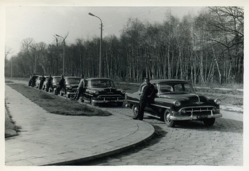 Kolumna samochodów państwowych. Lata 50. Pierwsze dwa auta Chevrolet Bel Air model z 1953 r., drugie dwa radzieckie Wołgi 21, ostanie dwa wozy Warszawy M20. Ustawienie samochodów nie było przypadkowe i odpowiadało randze urzędników danej instytucji najważniejsi jeździli Chevroletami, średni rangą Wołgami, a niżsi rangą krajowymi Warszawami