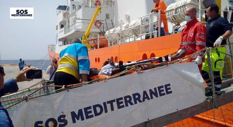 A migrant receives help when disembarking from the SOS Mediterranee ship Aquarius at the Italian island of Lampedusa in this handout received April 18, 2016. 