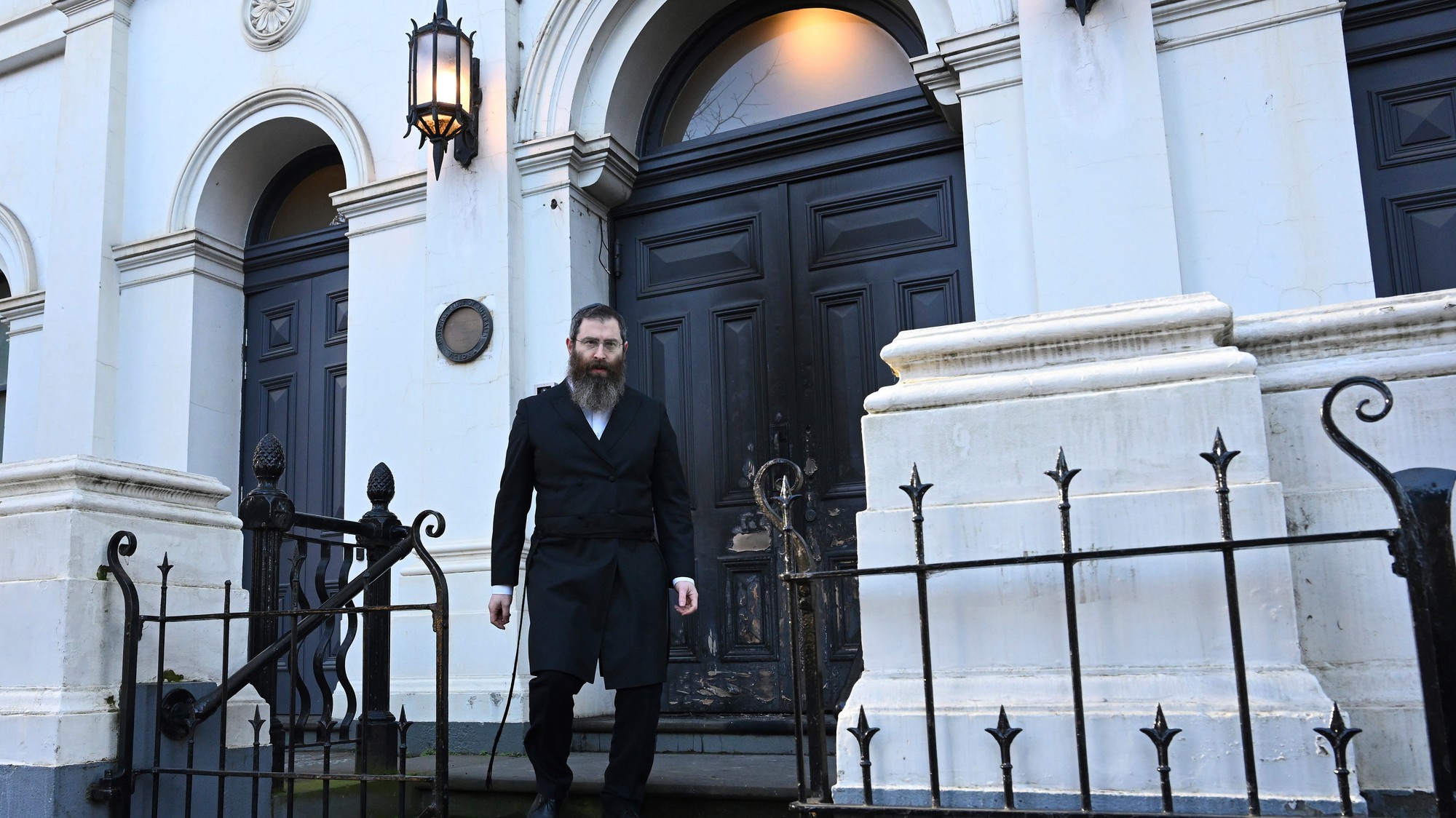Rabín Dovid Gutnick prechádza okolo poškodeného exteriéru Hebrejskej kongregácie East Melbourne 5. júla 2025.