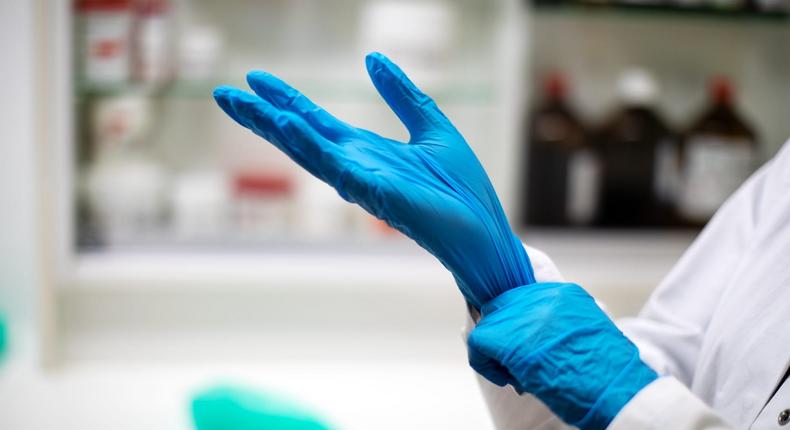 Close-up of a chemist putting on gloves in pharmacy.
