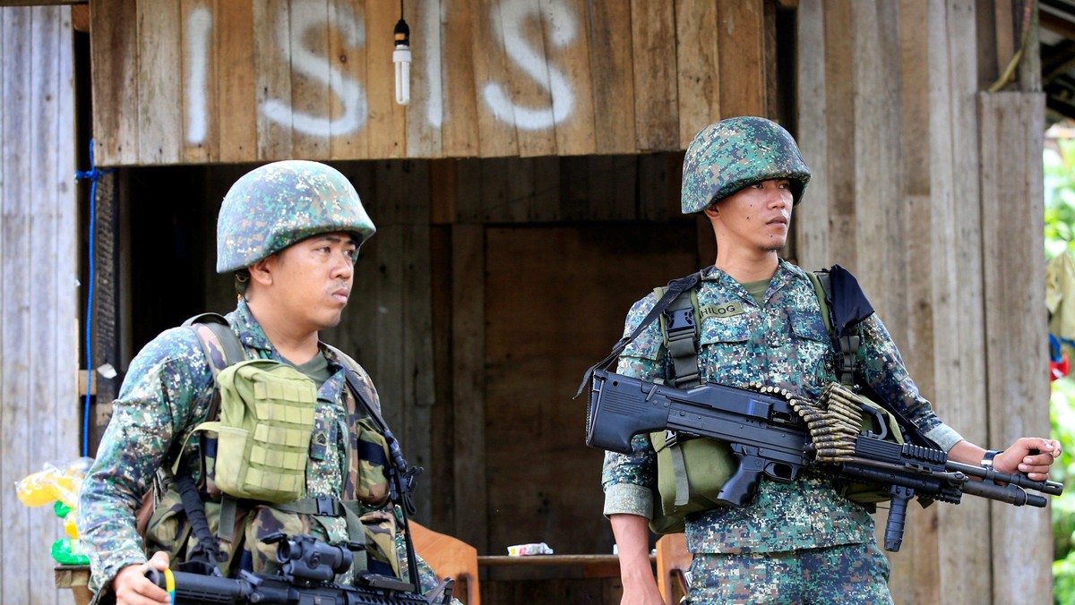 Soldiers stand guard along the main street of Mapandi village as government troops continue their as