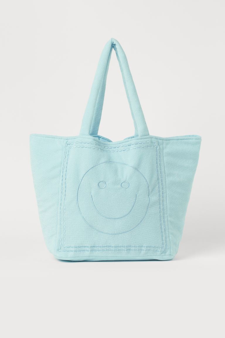 Cabas bleu avec Smiley brodé de H&M pour 24.95. 
