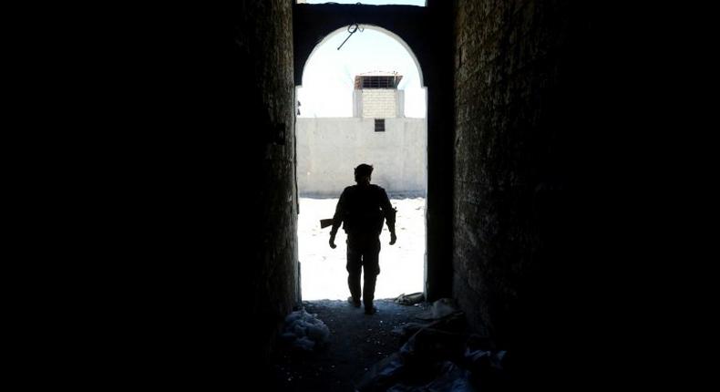 A member of the Syrian Democratic Forces (SDF) walks out of a building on June 27, 2017 on the western city limits of Raqa after the area was seized from the Islamic State group