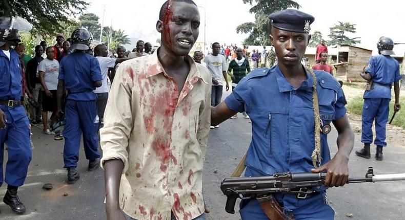 A riot policeman escorts an injured protester who was hit during clashes with riot police against the decision to allow President Pierre Nkurunziza to run for the country's third term presidency seat.