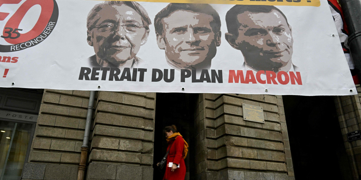 Pieszy przechodzi obok transparentu z portretami premier Elisabeth Borne, prezydenta Emmanuela Macrona i ministra pracy Oliviera Dussopta. Napis „brak emerytury dla zmarłych” to sprzeciw wobec rządowego planu reformy emerytalnej.