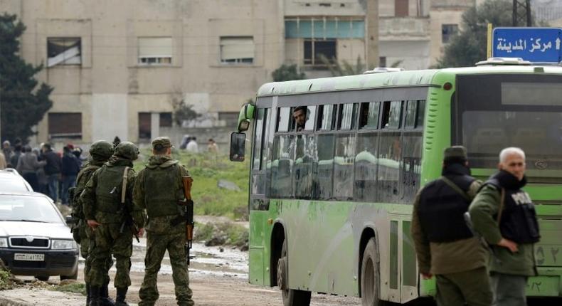 Russian military police stand guard during the evacuation of the last rebel-held district of Syria's Homs on March 18, 2017