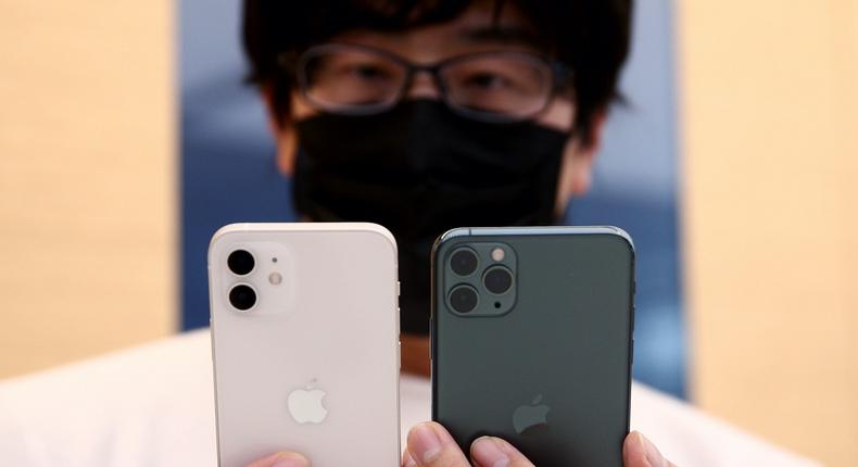 A customer holds the iPhone 12, left, and the iPhone 12 Pro, right.