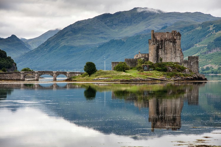 <strong>Twierdza Eilean Donan</strong>
<br></br>
Zamek Eilean Donan jest jednym z najbardziej rozpoznawalnych zamków w Szkocji. Strategicznie zlokalizowany na małej wysepce, z widokiem na wyspę Skye. Otoczony majestatycznym blaskiem zalesionych gór Kintail. okolica Eilean Donan zapiera dech w piersiach.
<br></br>
Po przybyciu na duży parking, goście docierają do jasnego, nowoczesnego centrum dla odwiedzających, w którym mieści się biuro biletów, sklep z upominkami i restauracja. Właścicielem zamku jest rodzina MacRae, której obowiązkiem jest zachowanie budynku i jego artefaktów dla narodu i przyszłych pokoleń.
<br></br>
Pierwszy zamek został założony w XIII wieku, aby chronić okolice przed najazdami Wikingów. Pierwotny zamek obejmował całą wyspę i uważa się, że został zbudowany z siedmioma wieżami połączonymi masywną ścianą osłonową. Przez stulecia zamek zmieniał się wielokrotnie z powodów, które do dziś pozostają tajemnicą.
<br></br>
Ważną datą w historii tego miejsca jest rok 1719. r., Wówczas to zamek okupowały hiszpańskie wojska z zamiarem wzniecenia kolejnego powstania Jakobitów. Kiedy rząd brytyjski dowiedział się, że zamek był zajęty przez przywódców jakobickich wraz z garnizonem żołnierzy hiszpańskich, wysłano tam ekspedycję trzech fregat marynarki królewskiej, by poradziły sobie z powstańcami. 
<br></br>
10 maja 1719 roku trzy silnie uzbrojone okręty wojenne zacumowały niedaleko zamku i zbombardowały go armatami. Mury o grubości do 5 metrów wytrzymały, ale ostatecznie zamek został zdobyty. Dowódca atakujących fregat odkrył w zamku 343 baryłki prochu, które posłużyły do wysadzenia zamku. Eilean Donan leżał w cichej ruinie przez kolejne niemal dwieście lat.
<br></br>
Zamek, który dziś cieszy się tak dużą popularnością, został zrekonstruowany jako dom rodzinny w latach 1912-1932 przez ppłk. Johna MacRae-Gilstrapa.
<br></br>
Odwiedzający mają teraz możliwość obejrzenia większości wspaniałych wewnętrznych sal z meblami z epoki, artefaktów jakobińskich; organizowane są także pokazy broni. Dla miłośników dzikiej przyrody przygotowano miejsca do obserwacji morświnów, delfinów, wydr i ptaków.
<br></br>