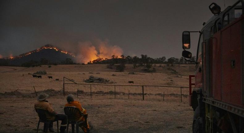 Volunteer firefighters watch as a bushfire rages on the outskirts of the town of Tumbarumba in New South Wales