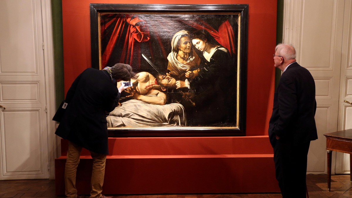 Visitors looks at a painting entitled Judith Beheading Holofernes during its presentation in Paris