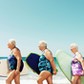 Three mature women on beach with surfboards