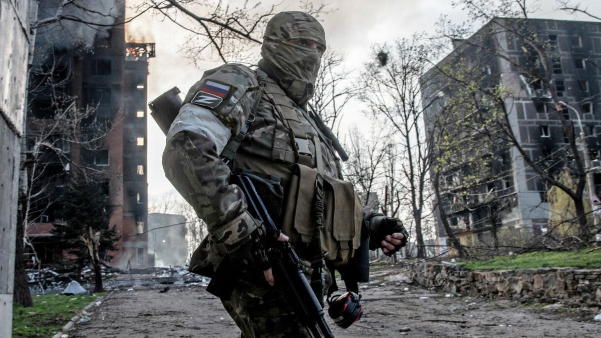 Rosyjski żołnierz stoi na tle płonącego bloku mieszkalnego w centrum Mariupola.