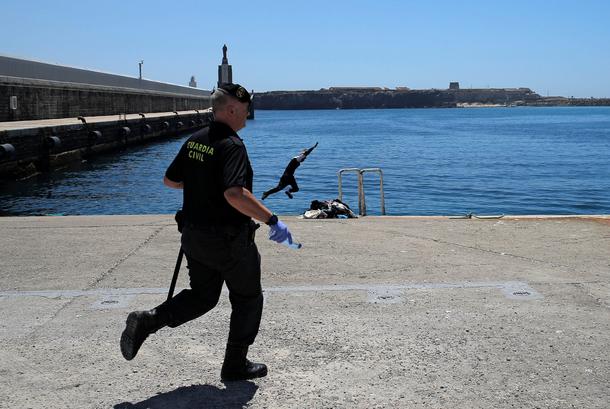 A migrant jumps into the sea as he tries to escape the Spanish civil guards after arriving on a resc