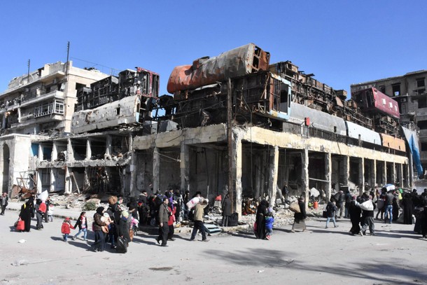 People, who left the eastern districts of Aleppo, carry their belongings as they walk in a governmen