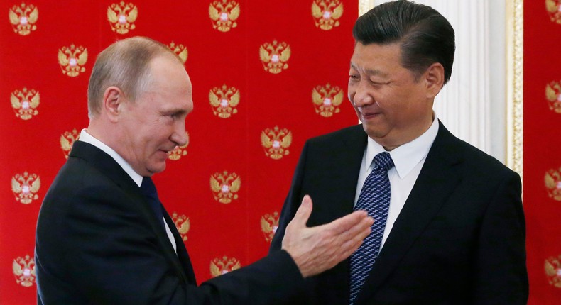 Russian President Vladimir Putin (L) gestures as he welcomes China's President Xi Jinping during an informal meeting in the Kremlin in Moscow on July 3, 2017.