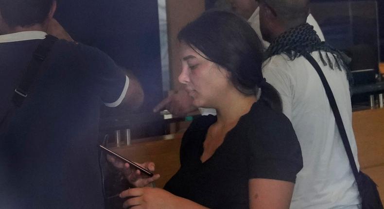 Lebanese Sali Hafez, center, accompanied by activists looks at her phone after breaking into a BLOM Bank branch brandishing what she later said was a toy pistol and taking $13,000 from her trapped savings accopunt, in Beirut, Lebanon, Wednesday, Sept. 14, 2022.