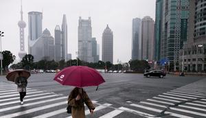 SHANGHAI, CHINA - FEBRUARY 24: A woman crosses a pedestrian crossing in wet weather in the Shanghai's financial district (Lujiazui) on February 24, 2018 in Shanghai, China.Vincent Isore/IP3