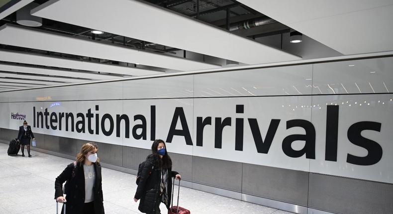 Passengers wearing face masks as a precautionary measure against COVID-19, walk through the arrivals hall after landing at London Heathrow Airport in west London, on January 15, 2021