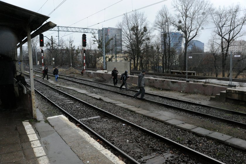 Podróżni przebiegają przez tory