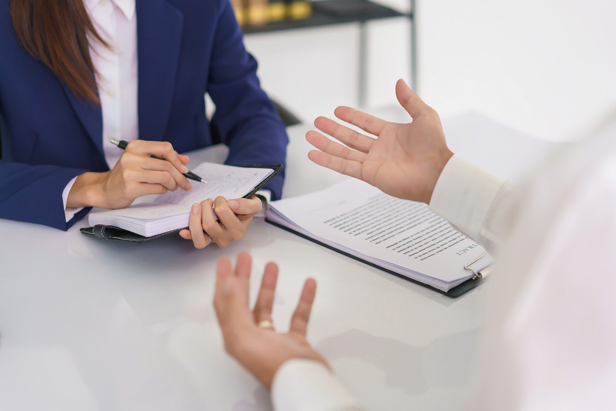 Dwie osoby prowadzące rozmowę przy stole w miejscu pracy