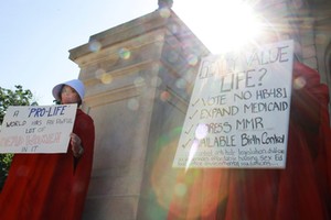 Protesters Houston and Martin hold signs against Georgia's anti-abortion heartbeat bill at Georgia State Capitol in Atlanta