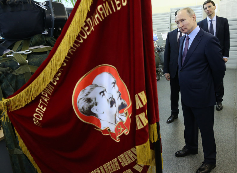 Władimir Putin obok flagi z podobiznami Włodzimierza Lenina i Józefa Stalina