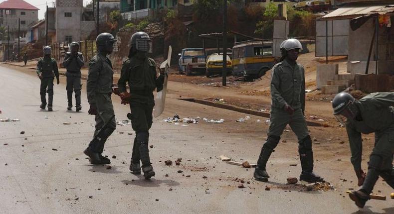 Security forces walk down a street filled with debris after protests in Conakry, Guinea, May 7, 2015. Youths in Guinea's capital blocked roads with burning tyres and clashed with security forces on Thursday, raising pressure on President Alpha Conde ahead of talks with the opposition aimed at resolving a dispute over the timing of elections. REUTERS/Saliou Samb