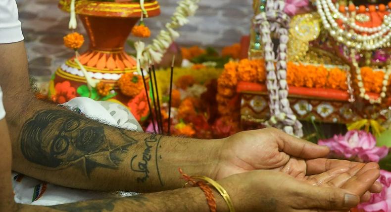 A fan with a tattoo of Amitabh Bachchan on his arm takes part in a ceremony praying for the Bollywood star's recovery from coronavirus in Kolkata