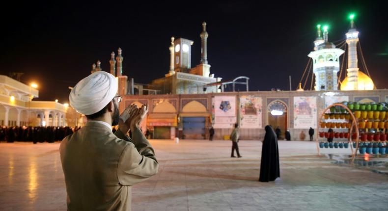 A cleric prays outside the Fatima Masumeh shrine in Iran's holy city of Qom on March 16, 2020, the day it was closed due to the coronavirus