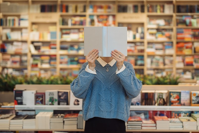 A,Young,Woman,Holds,A,Book,In,Front,Of,Her