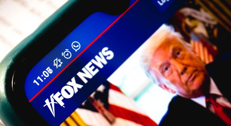 A close-up of the Fox News Channel website with a picture of President Donald Trump displayed on a smartphone.