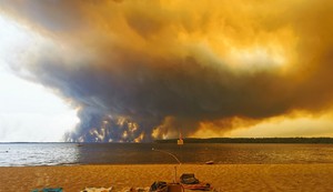 Posetioci plaže odmaraju se na plaži Mučik na obali jezera Lakano u Lakanou, na jugozapadu Francuske, dok požar besni u Žirondi, 24. jul 2026.