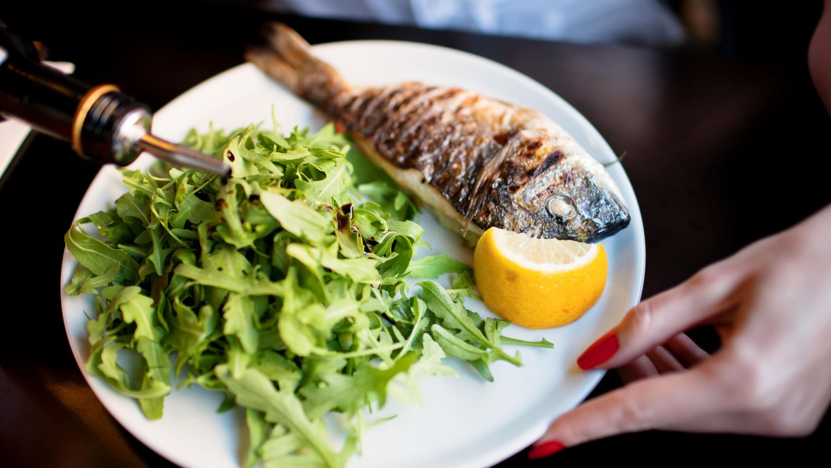 Grilled whole sea bream served with rocket salad and lemon