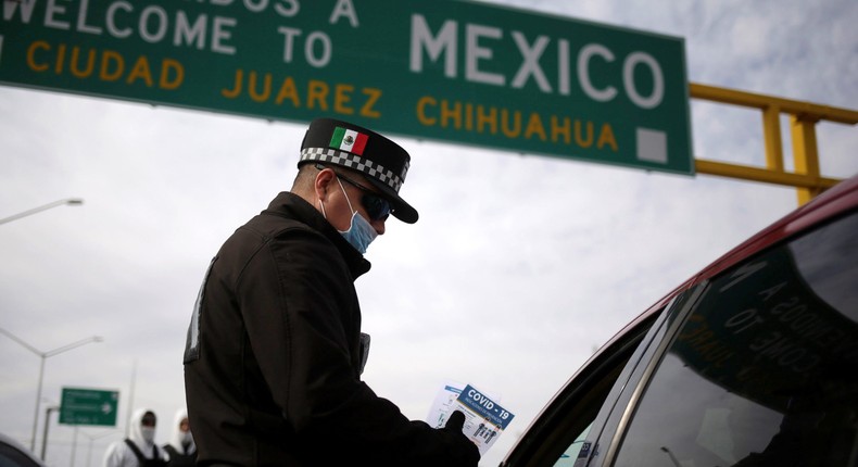 A police officer gives a leaflet with information about COVID-19 to a person entering Mexico in Ciudad Juarez, March 29, 2020.