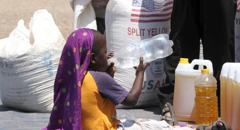 A child drinks water near the monthly food ration at a distribution center in rural Mupinga area in Chiredzi, Zimbabwe, October 6, 2015. REUTERS/Philimon Bulawayo