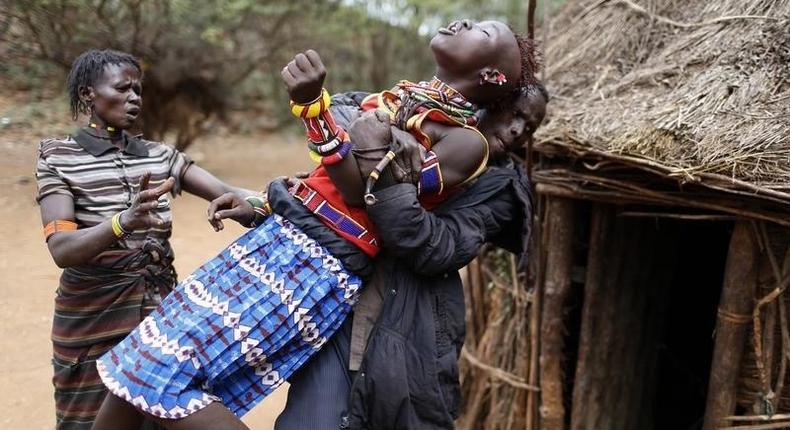 A man holds a girl as she tries to escape when she realised she is to to be married, about 80 km (50 miles) from the town of Marigat in Baringo County December 7, 2014. REUTERS/Siegfried Modola