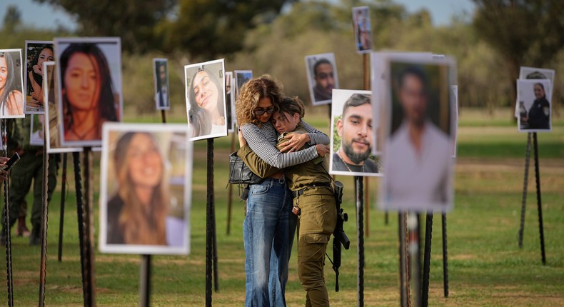 Israelis embrace next to photos of people killed and taken hostage by Hamas during the October 7 attacks.Ohad Zwigenberg/AP Photo