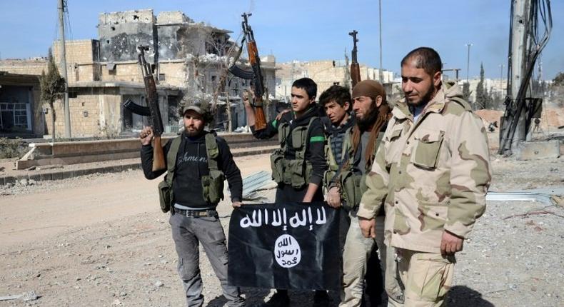 Rebel fighters, part of the Turkey-backed Euphrates Shield alliance, pose with an Islamic State group flag as they advance on February 20, 2017, towards the city of Al-Bab, some 30 kilometres from the Syrian city of Aleppo