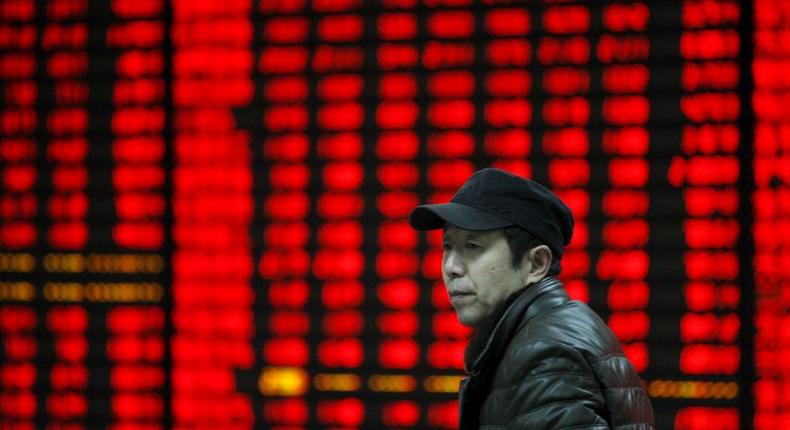 An investor walks past an electronic board showing stock information at a brokerage house in Huaibei, Anhui province, January 29, 2016 REUTERS/China Daily