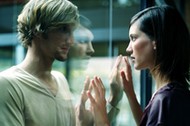 Young couple touching hands through glass, close-up