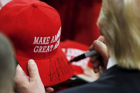 U.S. Republican presidential candidate Trump signs a hat at a campaign rally in West Chester