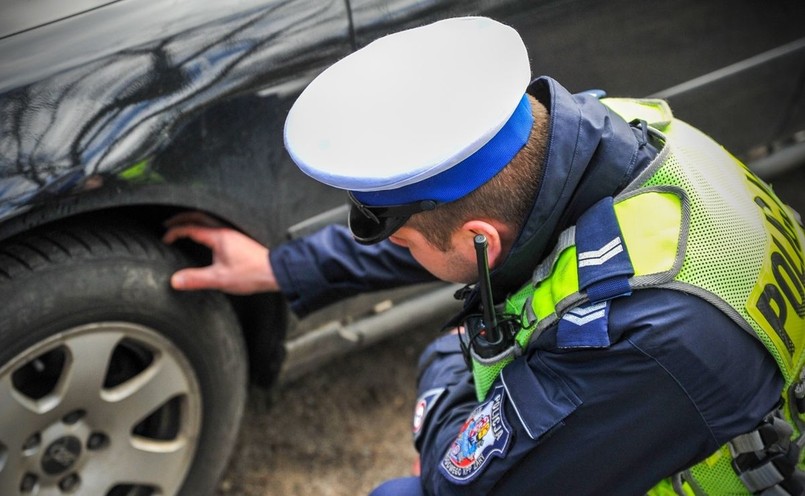 Policjant kontroluje stan techniczny opon