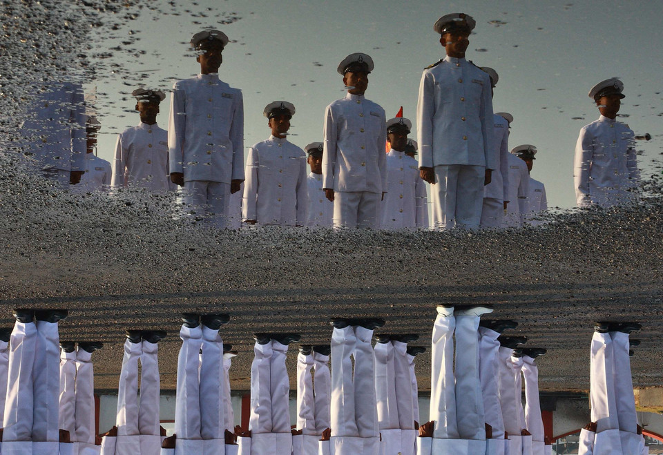 Indian Navy sailors are reflected in a puddle as they take part in a ceremonial parade during the Republic Day celebrations in Kochi