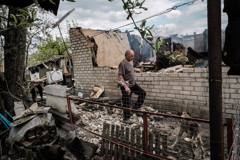 Mężczyzna na tle swojego zniszczonego domu w Łymaniu