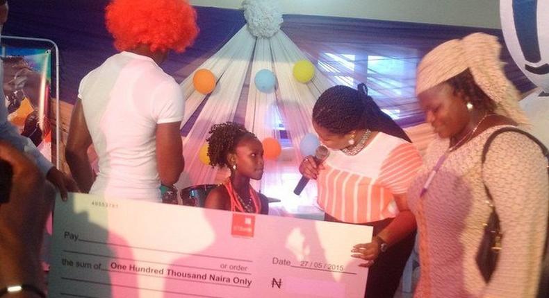 Dayo Amusa presenting a cheque of N100,000 to a winner at her event for the children
