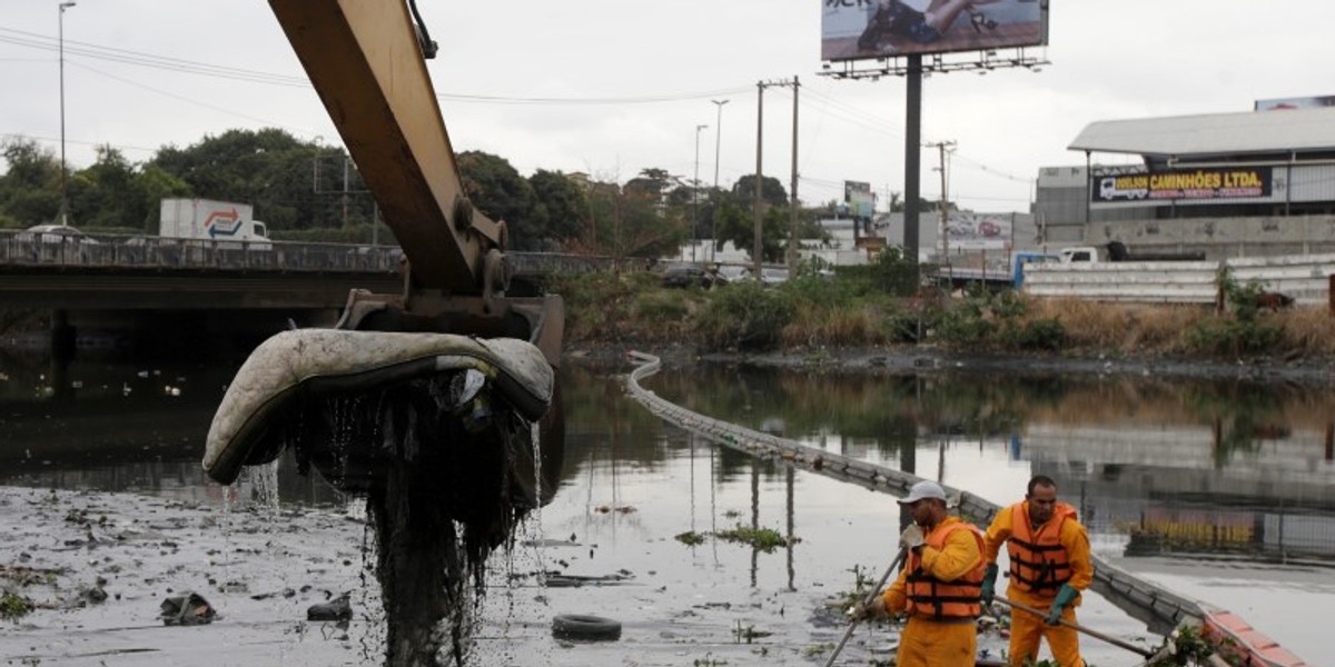 Men cleaning up garbage next to an ecobarrier at Meriti River, which flows into Guanabara Bay, in Duque de Caxias, near Rio de Janeiro.