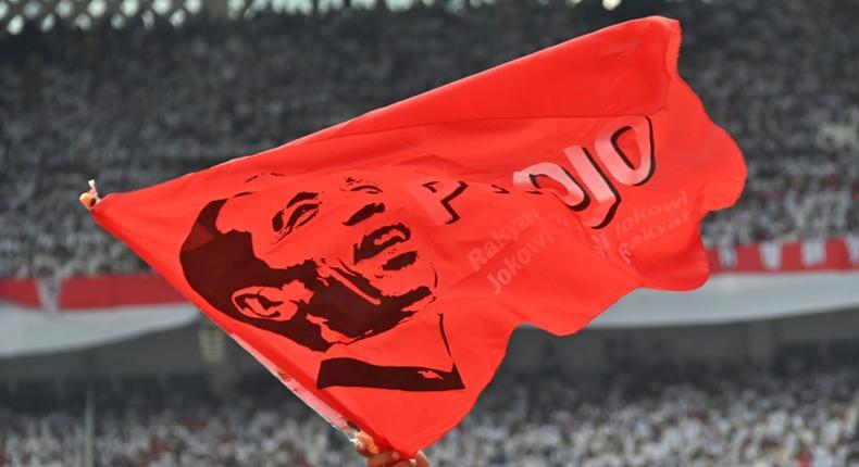 A supporter of incumbent Indonesian president Joko Widodo waves a flag bearing his portrait at an election rally in Jakarta